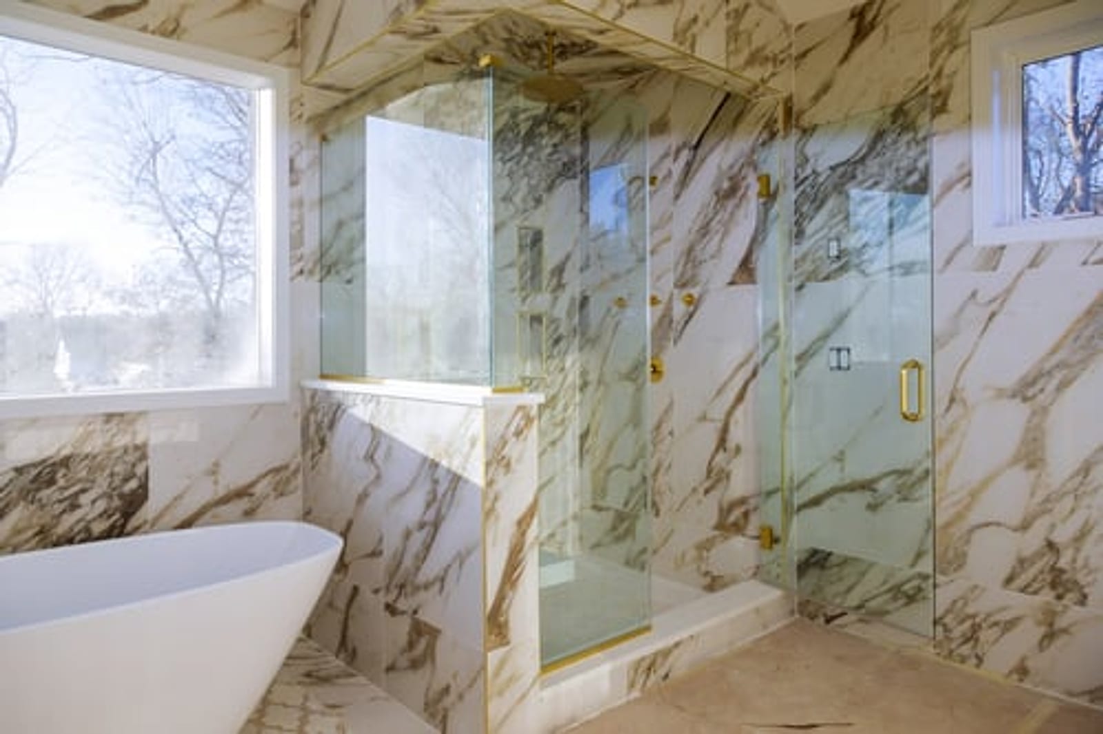 Marble-tiled walk-in shower with a glass enclosure completed in an Oklahoma City bathroom remodel