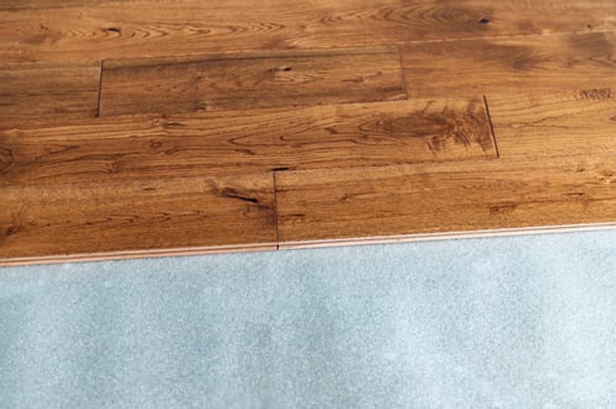 Close-up of finished oak hardwood flooring meeting carpet at a clean transition in an Oklahoma City home