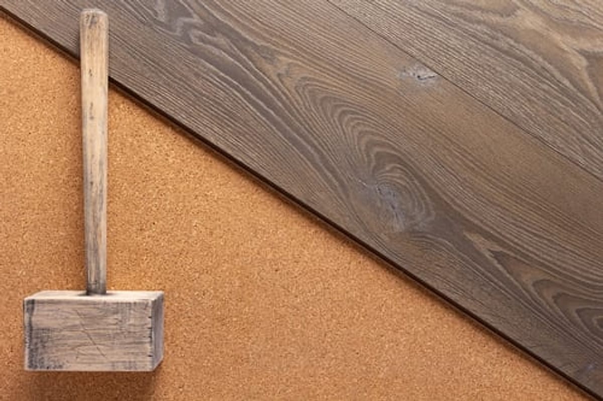 Wide dark oak hardwood planks being installed over cork underlayment with a tapping block in Oklahoma City