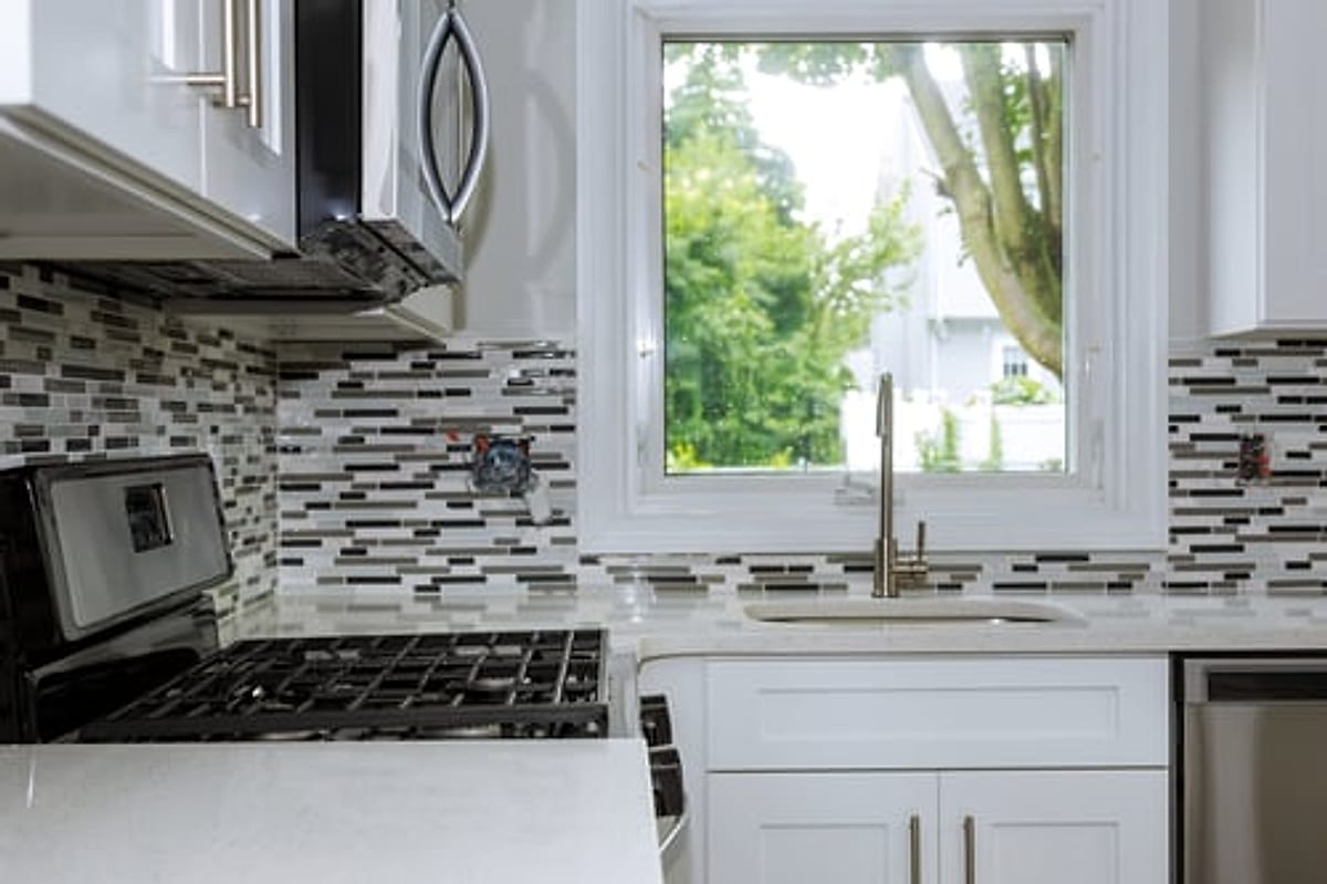 Renovated Oklahoma City kitchen with white shaker cabinets, quartz counters, and a mosaic tile backsplash