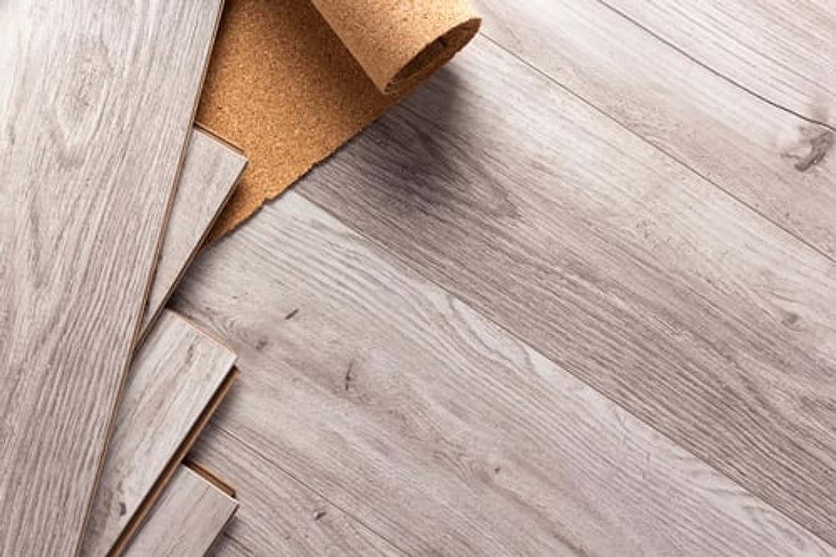 Grey luxury vinyl plank flooring being installed over cork underlayment in an Oklahoma City home